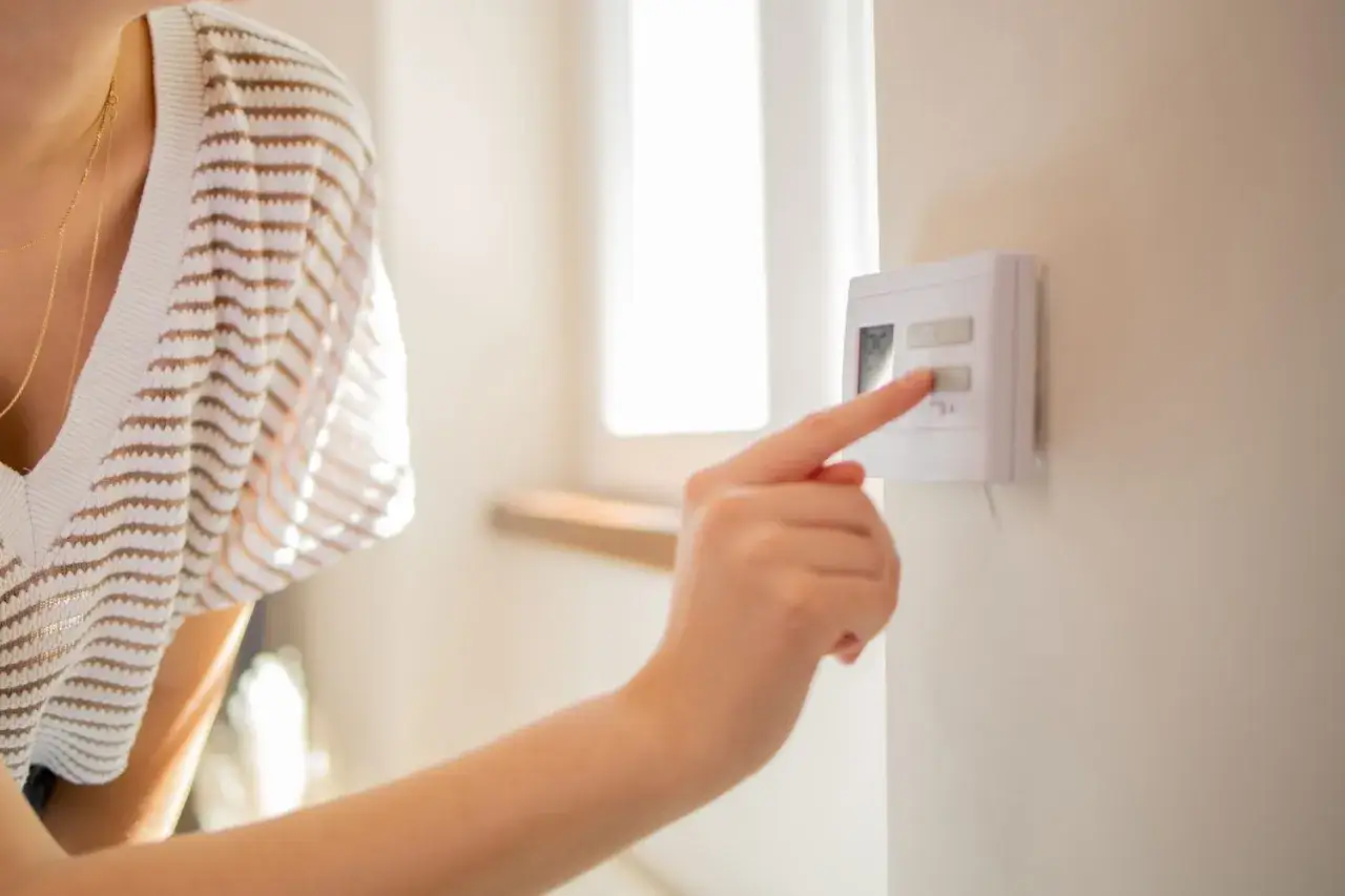 Mano ajustando el termostato. &iexcl;Uf, 26 grados es calor!